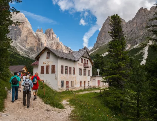 Group of people walking up a hill towards a white building