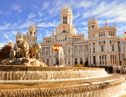 Shot of the Plaza de Cibeles, Spanish flags flying around it.
