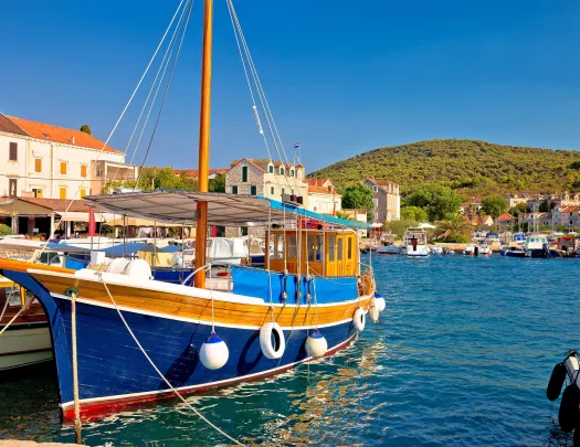 Blue and orange boat docked, with a small town in the background