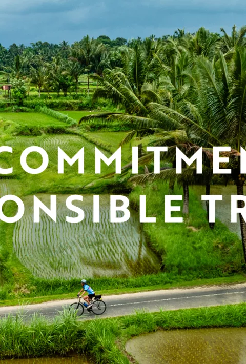 Cyclist riding through fields, overlay text: Our commitment to responsible travel