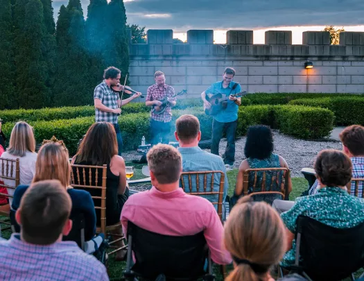 Group of people sitting and watching a small band play outdoors