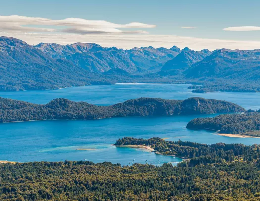 Sky view of a large lake, surrounded by tall mountains and trees