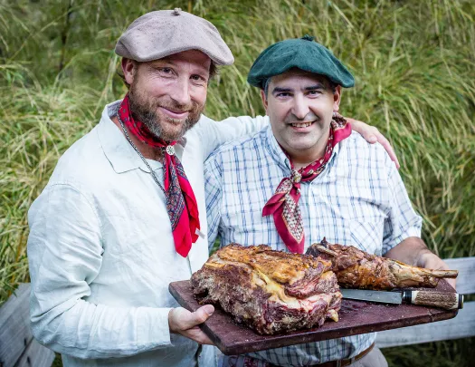 Two locals with meat platter, smiling at camera.