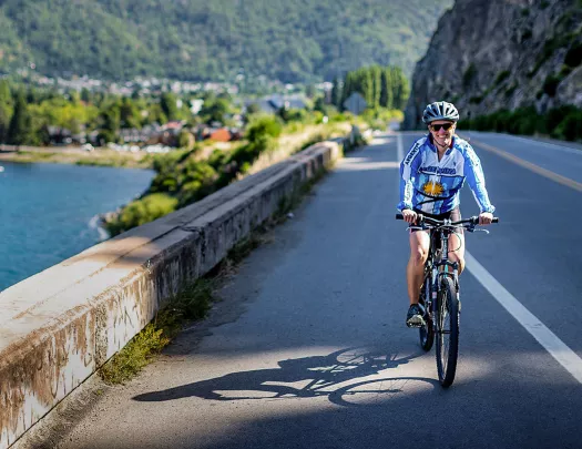 Guest cycling past lake, road, town behind them.
