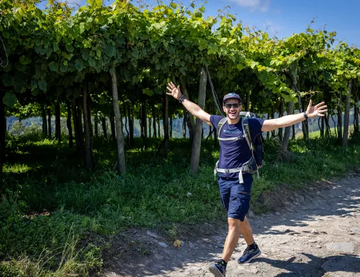 Man with arms wide open in front of vineyard