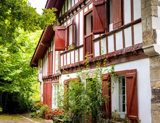 Housefront shot of red and white cottage among forest.