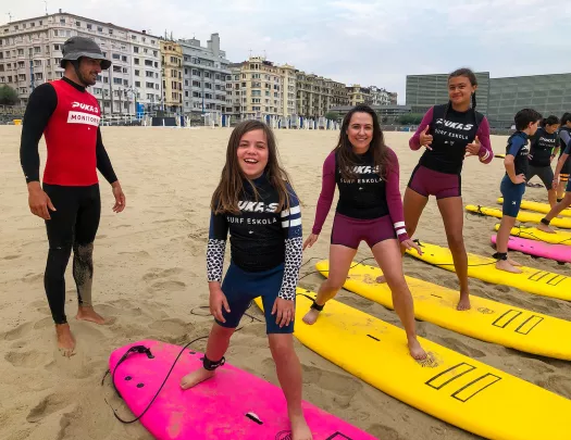 Group of young guests at surf lesson, instructor behind them.