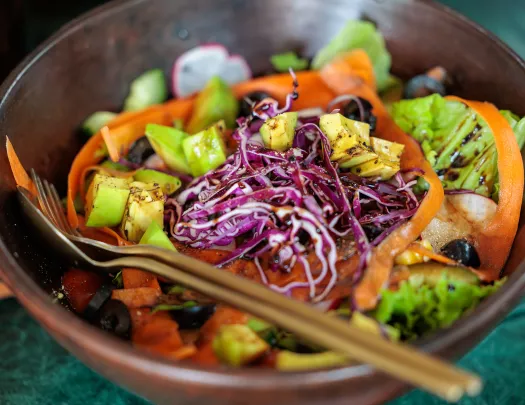 Bowl of vegetables and cabbage, with a salad dressing on top