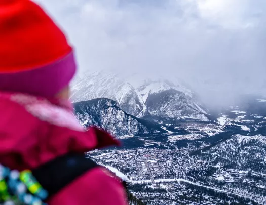 Over the shoulder shot of guest looking towards snowy town in distance.