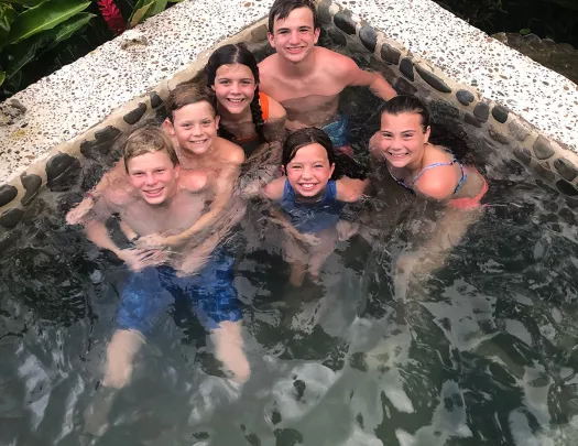 Six young guests in hot tub, looking up at camera.