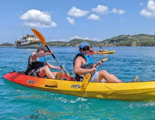 Two boys in a yellow kayak, paddling in the ocean