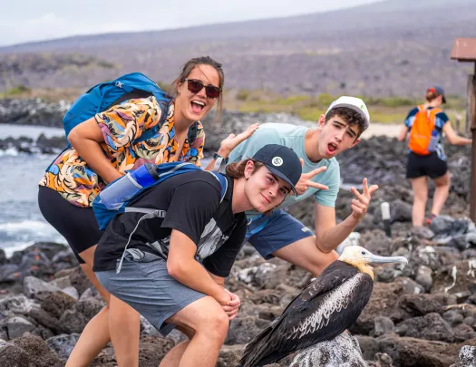 Three teenagers pose with a bird
