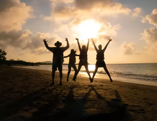 Three peoples silhouettes as they jump against the sunset