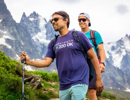 Two men using hiking poles, walking through a trail on a mountain