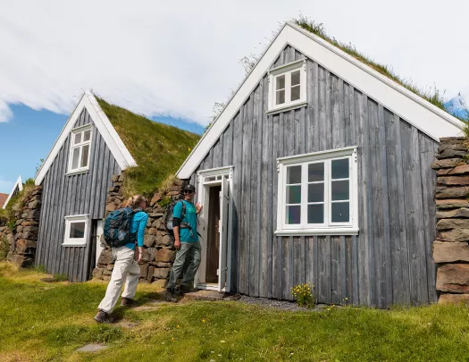 Man and woman smiling while entering a wooden cottage