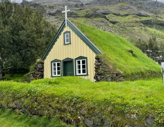 Small grass-roofed countryside church, overcast sky.