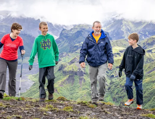 Man and women with two kids, walking on a dirt path with fog-covered mountains in the background