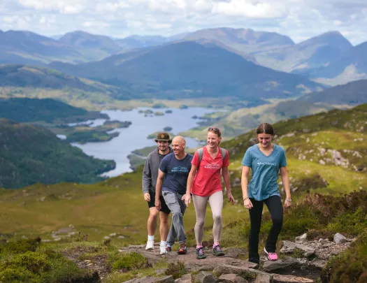 Two men and two women hiking on a stone hill, with a lake in the distance