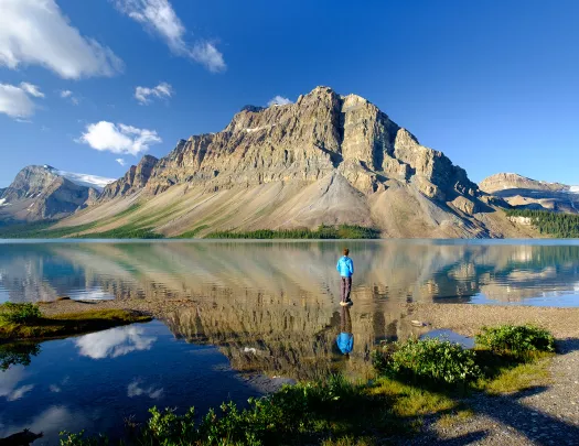 Wide shot of large lake, guest looking towards craggy mountains.