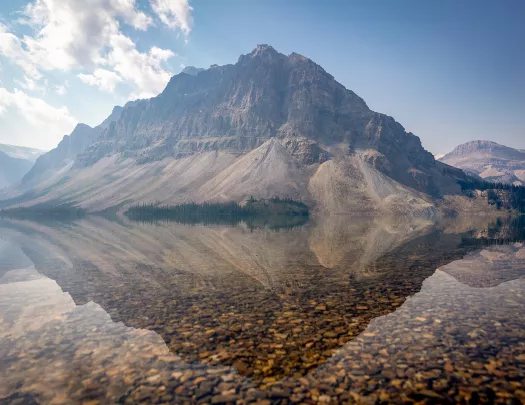 clear reflective lake next to a mountain