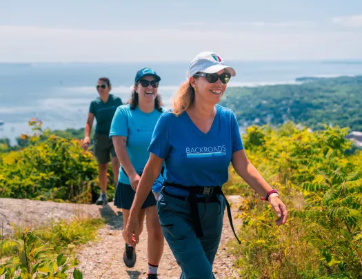 Three women smiling as they are hiking on a dirt trail