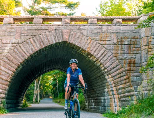 Woman smiling while riding a bike through a brick tunnel