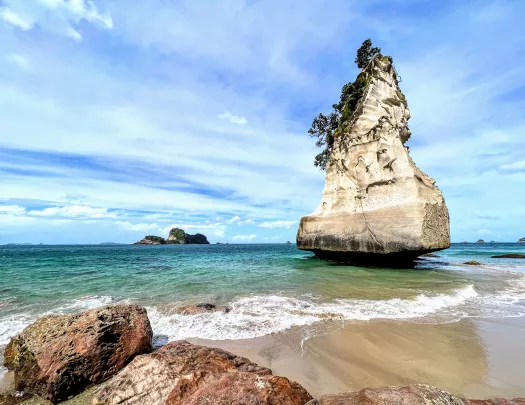 Tall rock formation by the beach in New Zealand