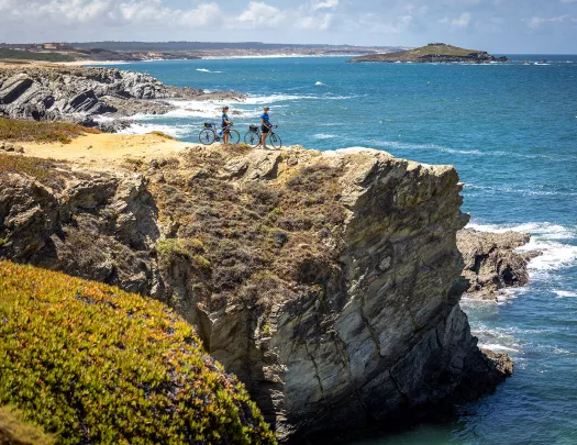 Two bikers resting on a cliff overlooking the sea