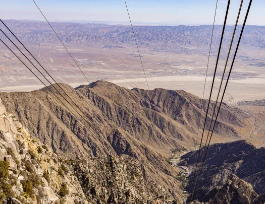 Wide shot of desert landscape, cables/wires in foreground.