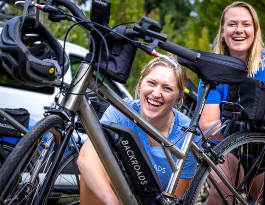 Two women smiling while standing next to an e-bike