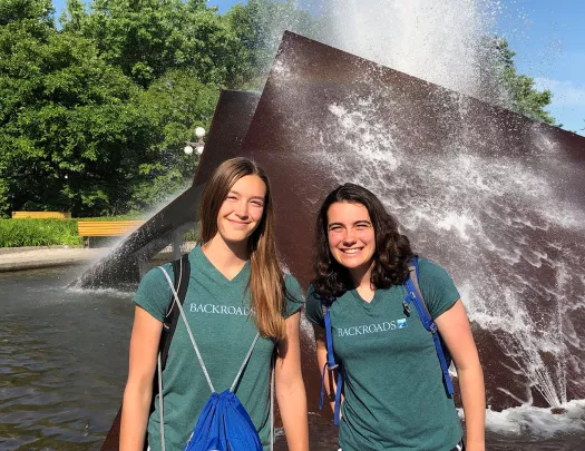 Two young guests smiling in front of a water sculpture.