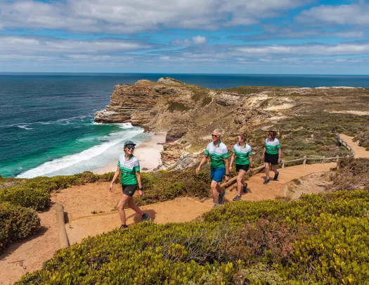 Four people hike up a sandy beach front road