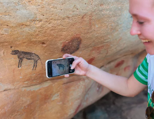 A person takes a photo of cave drawings