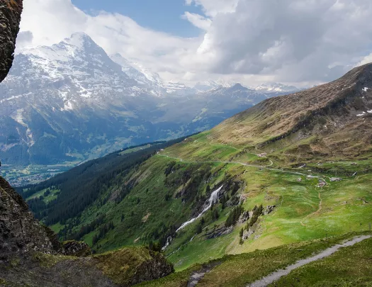 Wide shot of large mountain vista, small roads, hillsides, mountains in distance.
