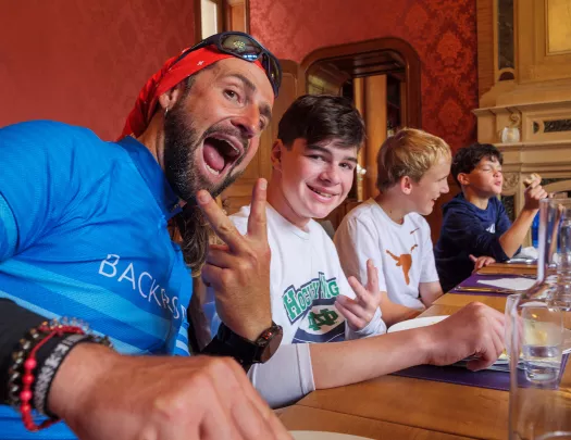 Man smiling and holding up a peace sign, with a younger teen next to him