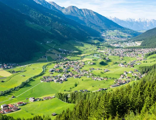 Small town scattered across a large grass valley, surrounded by large mountains