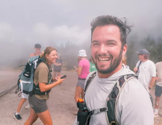 Group of people smiling while walking through a foggy trail