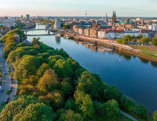 Long river along a city with large trees to the left and city buildings to the right