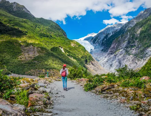 Woman hiking on mountainous, glacial trail in New Zealand.