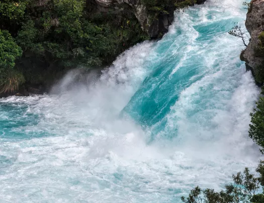 Wide shot of vibrant blue rushing waterfall.