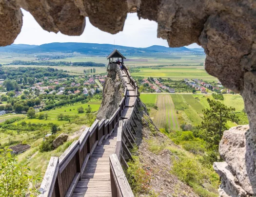 Large wooden pathway on top of a hill, overlooking a large grass valley and a small town