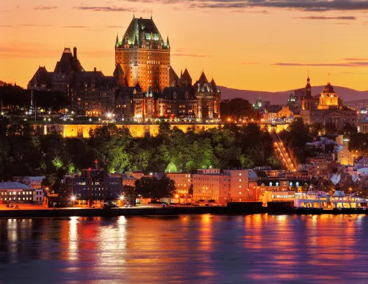 Wide shot of the Fairmont Le Château during sunset, river in foreground.