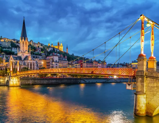 Illuminated suspension bridge leading to a rustic town