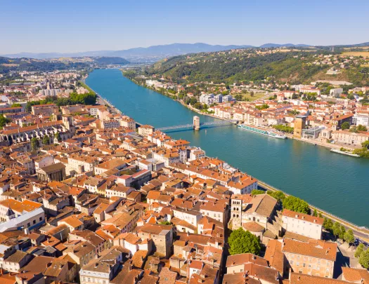 Brown and white buildings connected by a single bridge over a river