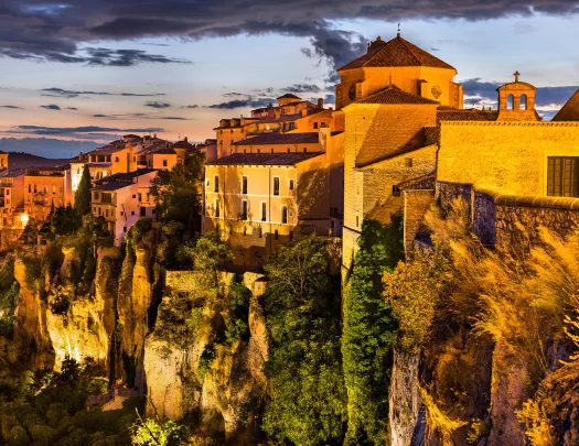 Sunset-lit cliffside, white houses above.