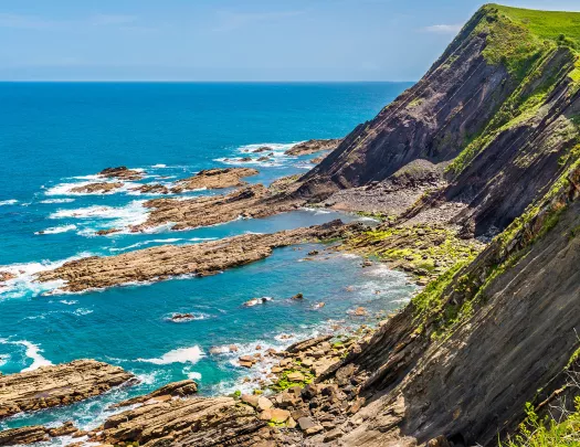Large cliff with rocks peeking from the ocean below