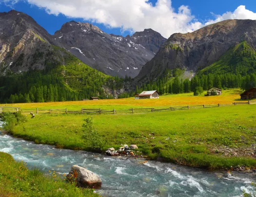 Rushing stream alongside farmlands at the base of a mountain in Slovenia.