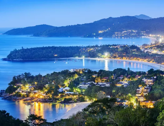 Sky view of city illuminated by lights, with the ocean in the background