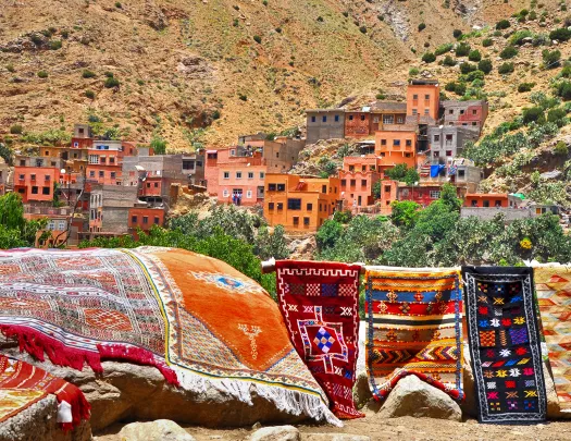 Shot of vibrant desert valley town, tapestries in foreground. 