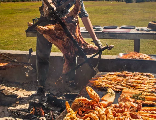 Man grilling seafood while carrying a pig on a rotisserie